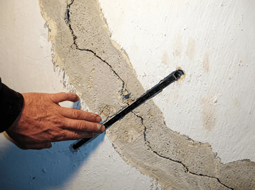 A wall with a large crack is being inspected by a professional in Nashville, TN
